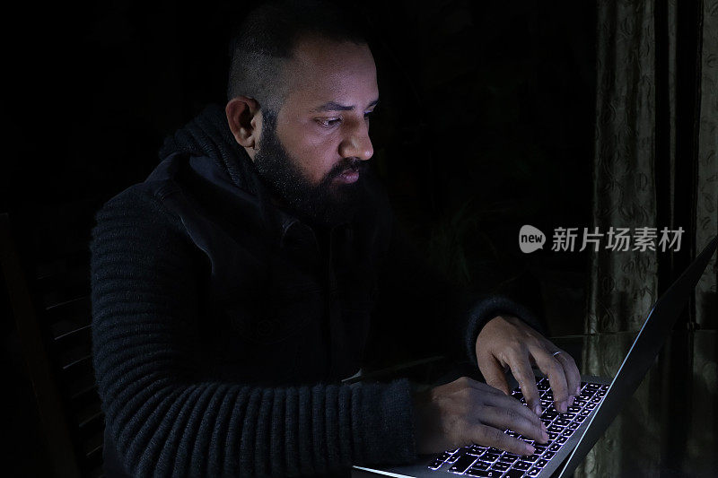 Image of male, asian computer hacker / programmer wearing hoodie with dark programming computer code background, Internet crime concept
